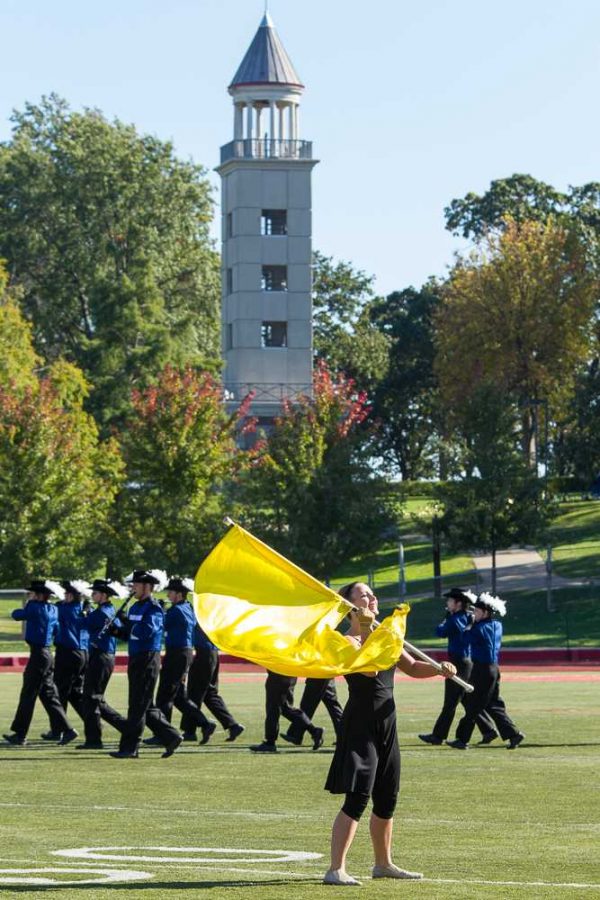 The  flag twirler waves a vibrant yellow flag during the performance. 