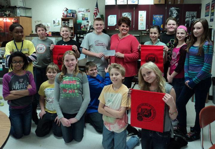 WMS students in Trish Smith's Life 101 class deliver a check for $100 to Stormy Taylor for the Big Brothers and Big Sisters program. Money was earned through the sales of Tiger sports bags. Left to right in back row:  ShaKeysha Loving, Dalton Edwards, Ayden Dennis, Cal Taylor, Stormy Taylor, Scarlet Howard, Emily Wooten, Morgan, Phelps, Mary Crets Left to right in front row:  Lawren Louis, Johnathen Likens, Bailey Tucker, Andrew Bailey, Justin Chapman, Cadence O'Connor (not pictured: Faith Woodward)