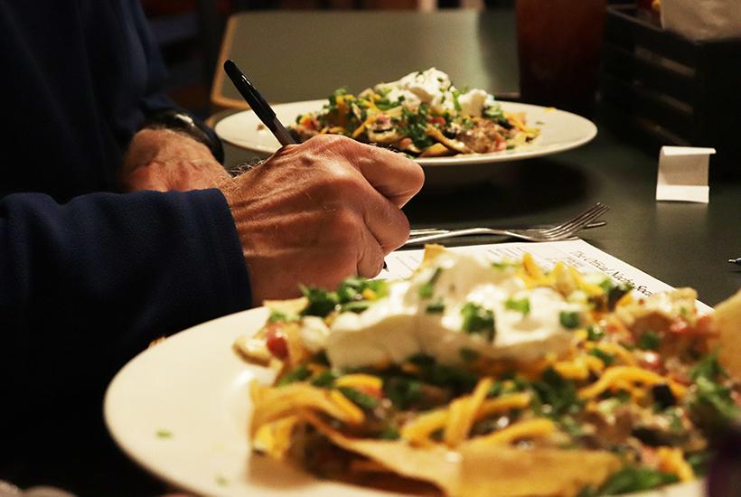 Ron Bowman, member of the Nacho Society, writes his ratings on the scorecard while eating his nachos. (Photo by Kaitlin Brothers / News Editor)