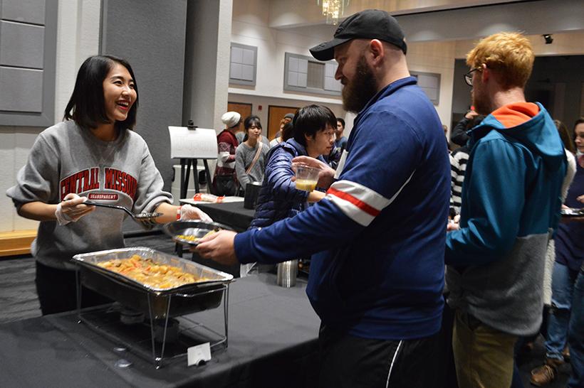 Kie Rokkenguchi, junior communication student, serves community member Shawn Robertson Nikujyaga, which is a Japanese dish made up of beef, potatoes, onions, carrots and more. (Photo by Erin Wides/ Features Editor)