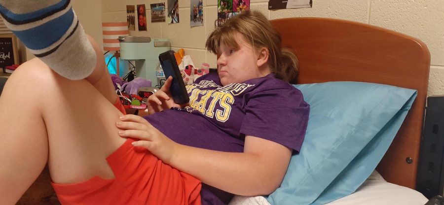 Hailey is a freshman THRIVE student who lives in Ellis. She has a roommate, and they both like anime. She is in this photo watching a YouTube video on her phone.