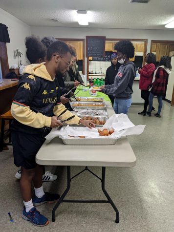 This is a side view of students serving food to other students.