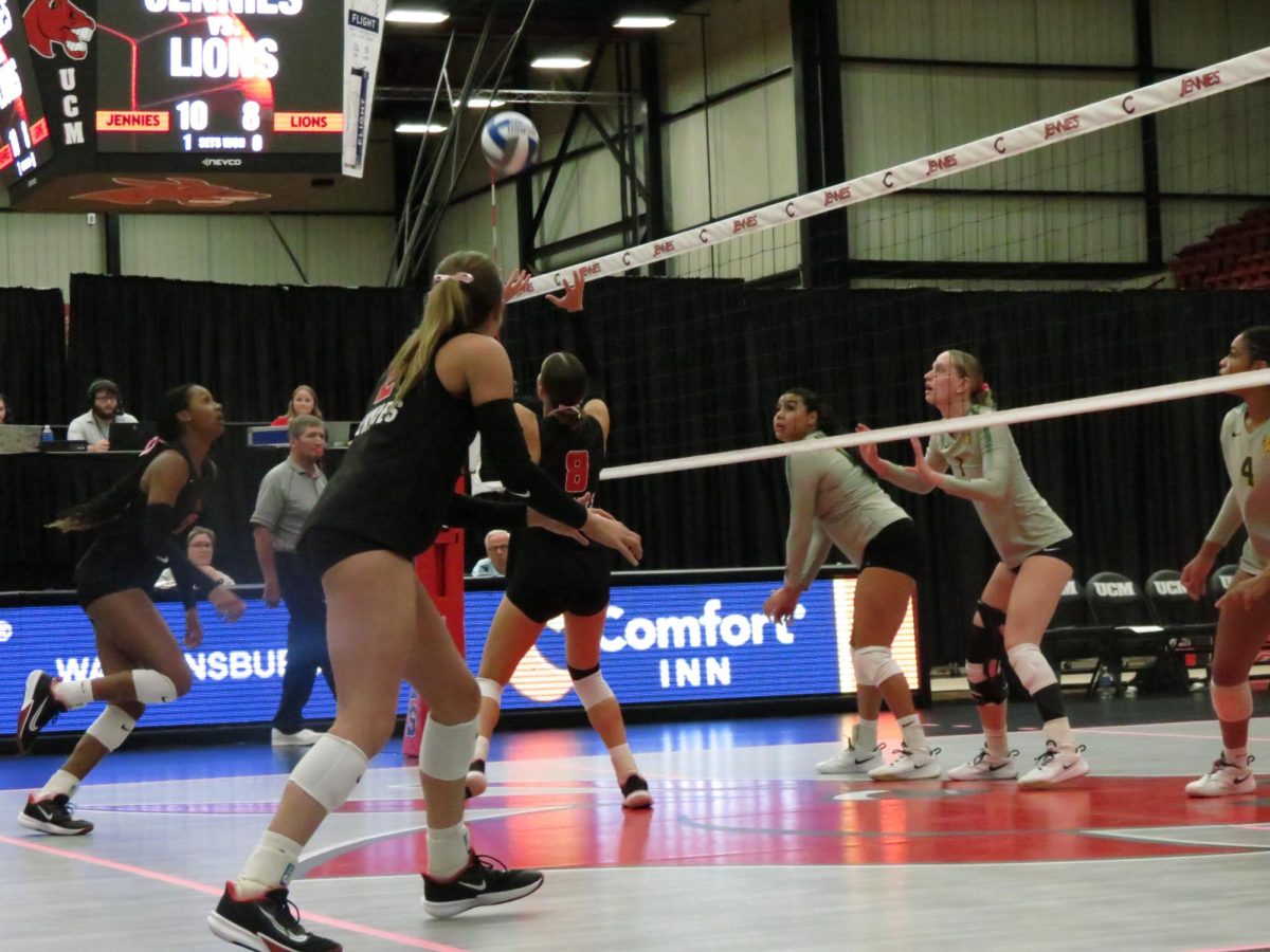 : Senior setter Kayla Baer (left) sets the ball high for freshman middle blocker Bria Dawson (right) to spike the ball, while junior opposite Lauren Blake (middle) prepares to block against a return hit on Oct. 7 at the Jerry M. Hughes Athletics Center. The Jennies defeated the Missouri Southern Lions 3-0.